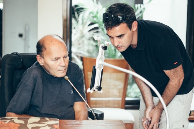 A paralyzed man and a standing man looking at a touch-free smartphone